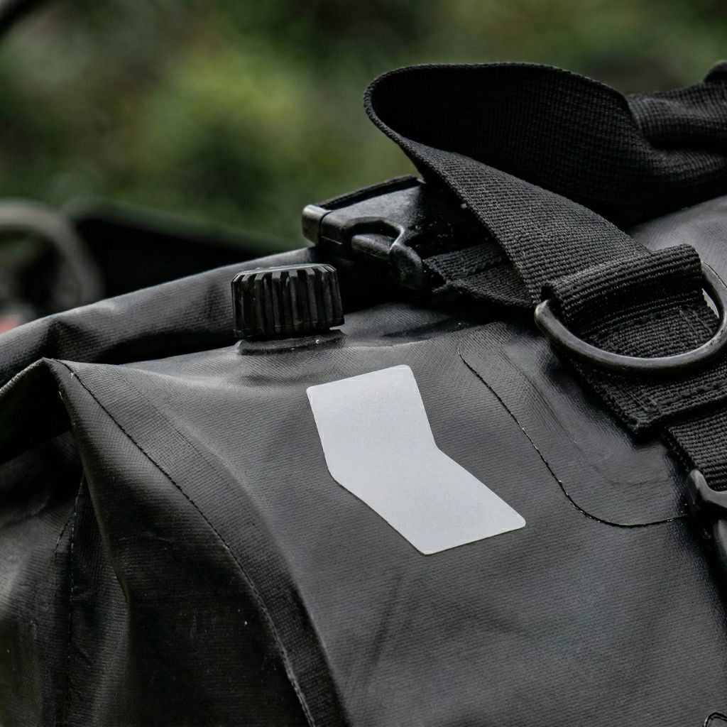 Gros plan sur la fermeture roll-top et bande réfléchissante grise d'un sac de voyage moto étanche noir Image