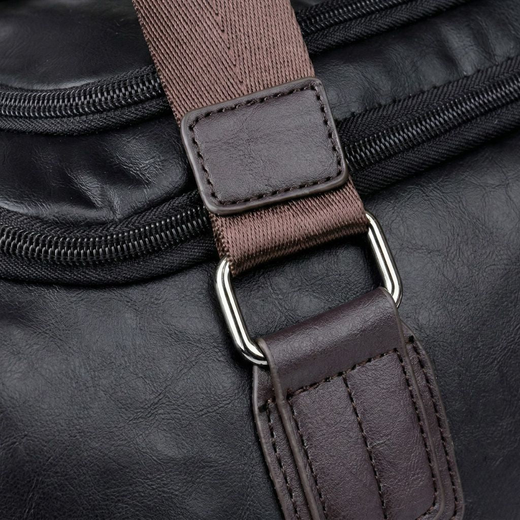 Détail anneau D et crochet de bandoulière du Duffle Bag cabine, métal argenté et sangle marron rivetée