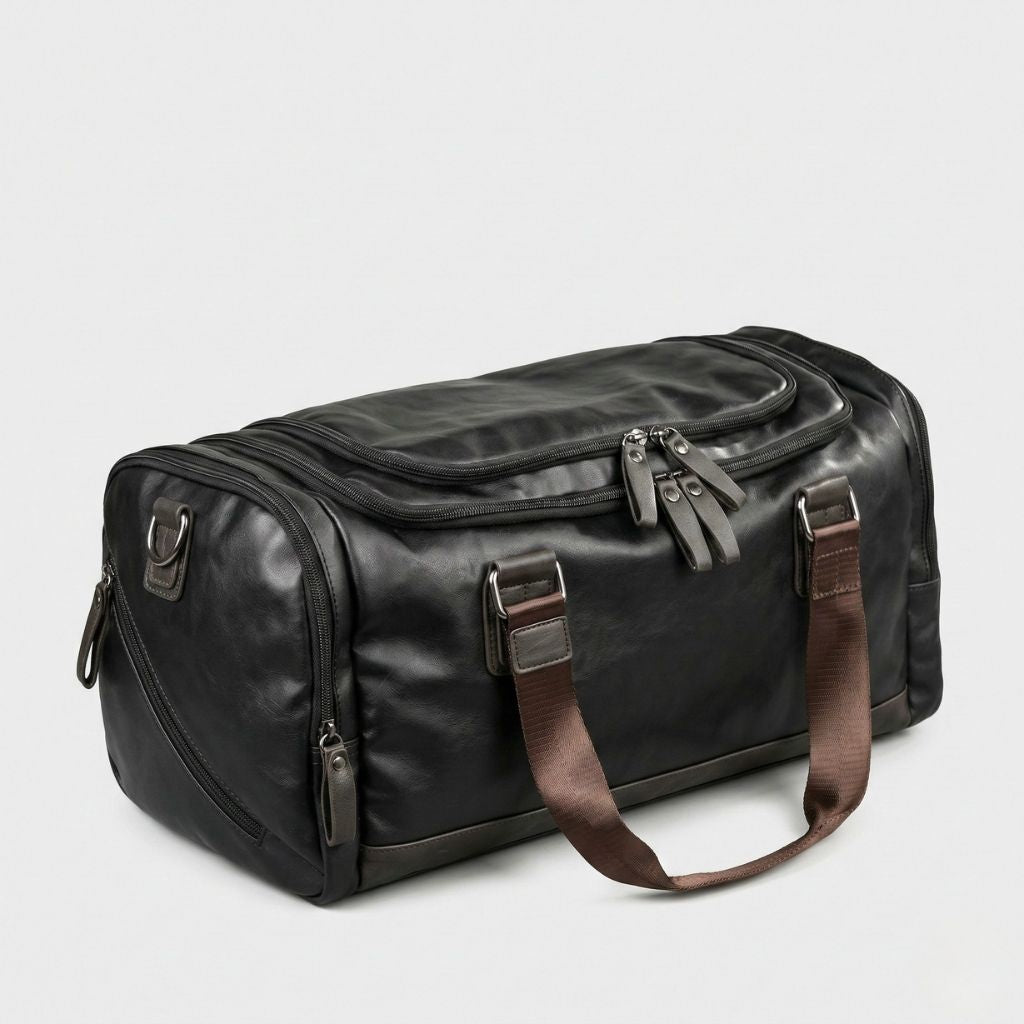 Duffle Bag cabine noir posé au sol, vue trois-quarts droit, bandoulière marron détachée et zips apparents
