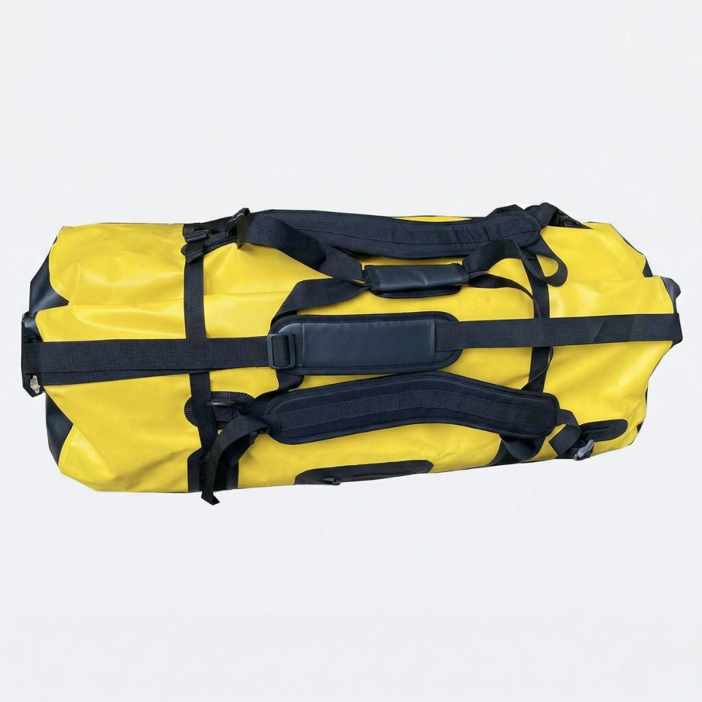 Grand sac de voyage étanche jaune et noir, vue de dessus montrant les bretelles dorsales et la poignée centrale