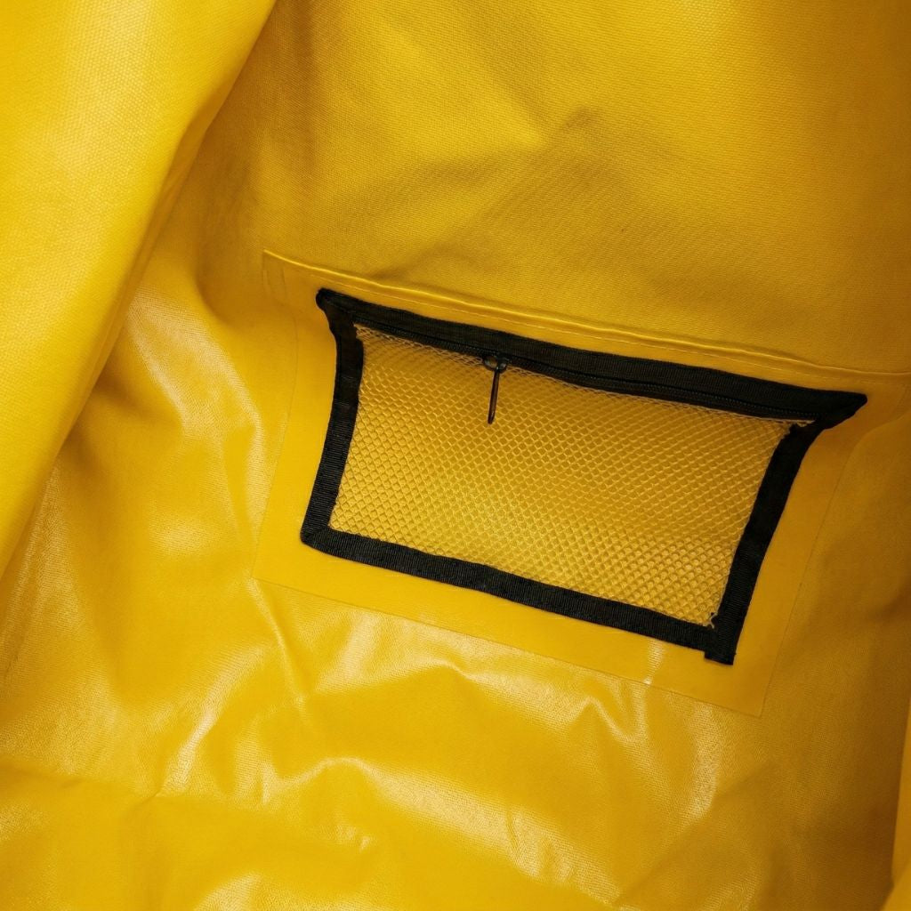 Intérieur du sac étanche jaune, poche frontale en filet noir zippée pour ranger les petits accessoires de voyage