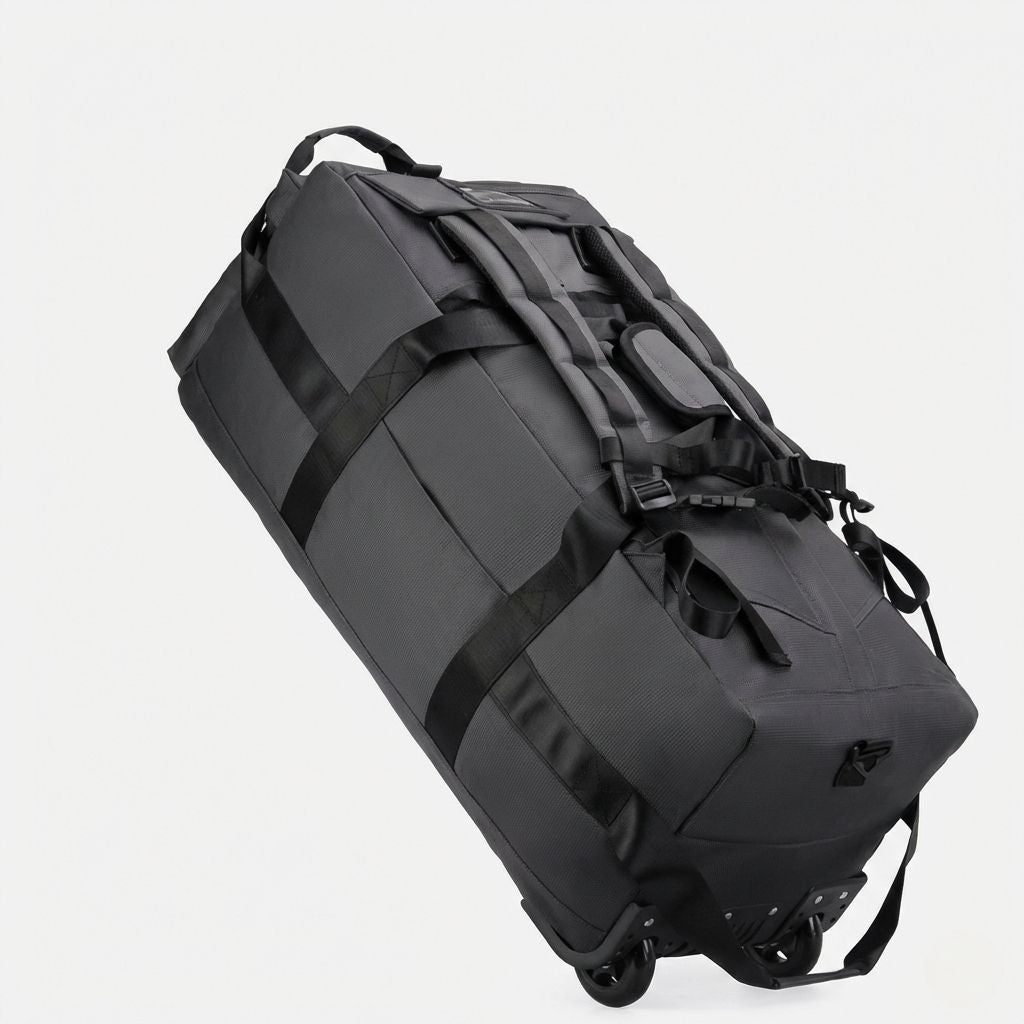 Sac de voyage gris anthracite en mode trolley incliné, roulettes doubles noires visibles en vue plongeante