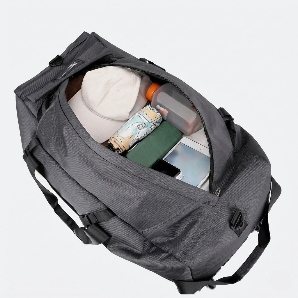 Vue plongeante dans le compartiment principal d'un grand sac de voyage gris avec chapeau, gourde et tablette Image
