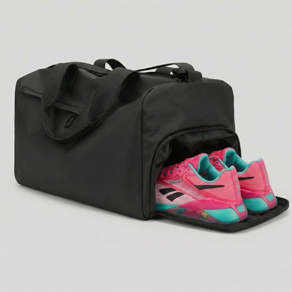 Sac de sport voyage noir avec compartiment chaussures latéral ouvert et baskets rose fluo et cyan insérées Image