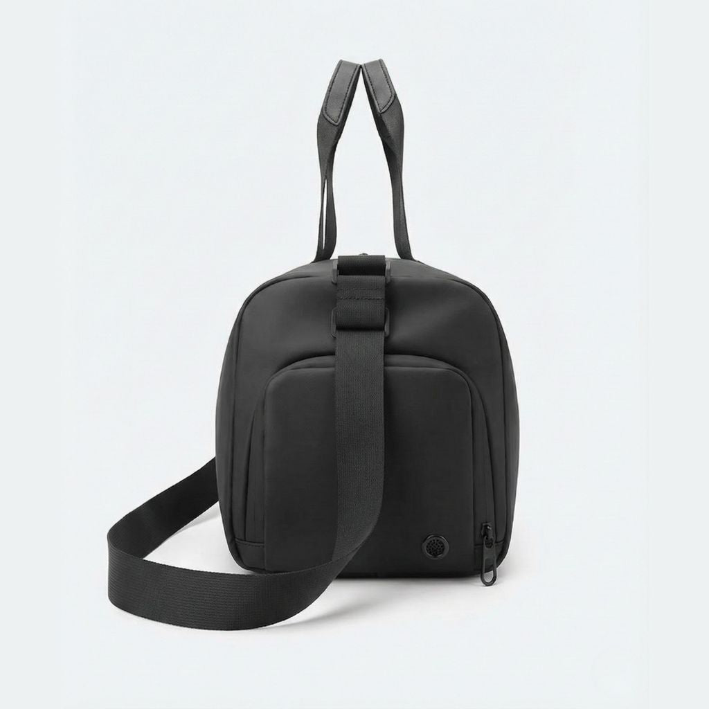 Dos du sac de voyage sport homme noir avec poche latérale zippée, lanière trolley et bandoulière