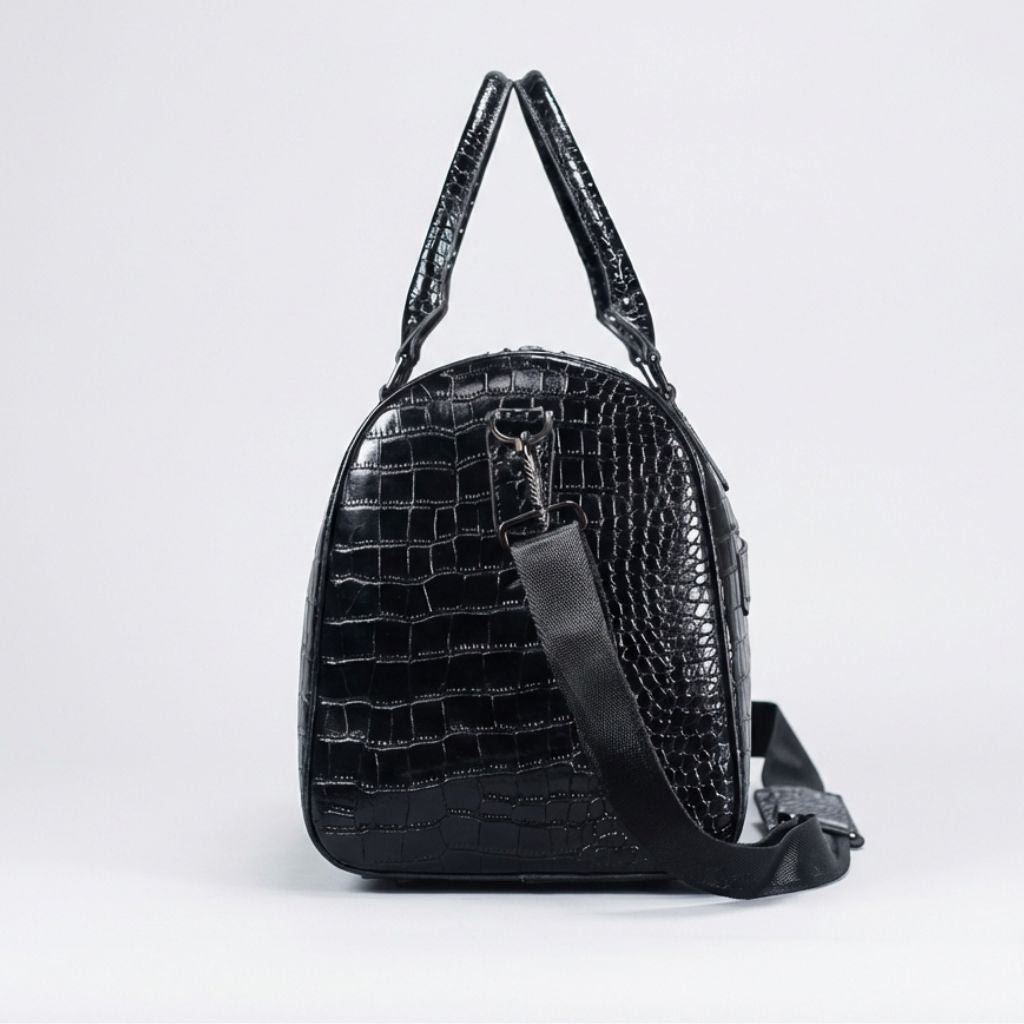 Vue latérale du sac de voyage croco noir brillant, panneau arrondi et anneau d'attache de bandoulière