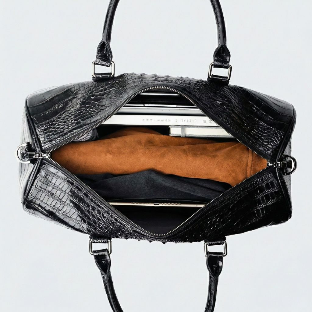 Intérieur ouvert d'un sac week-end en cuir noir brillant croco, doublure caramel et poche plate pour ordinateur. Image