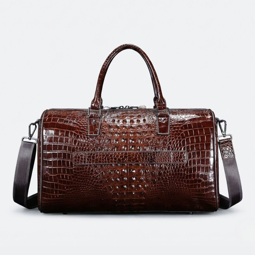 Vue de face du sac de voyage cuir croco marron, poche plate avant et bandoulière en tissu noir réglable