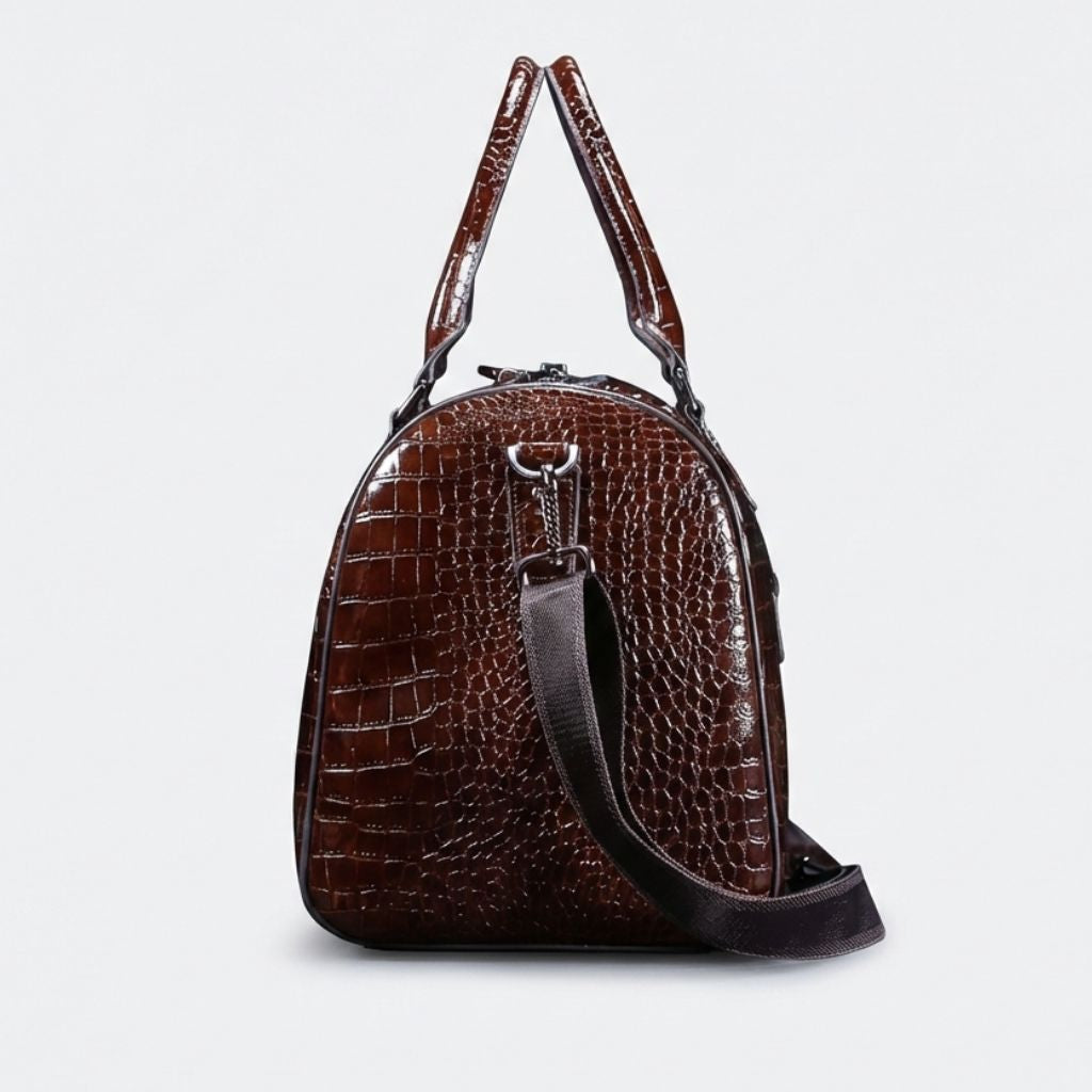 Vue latérale du sac de voyage croco marron brillant, panneau arrondi avec anneau d'attache bandoulière