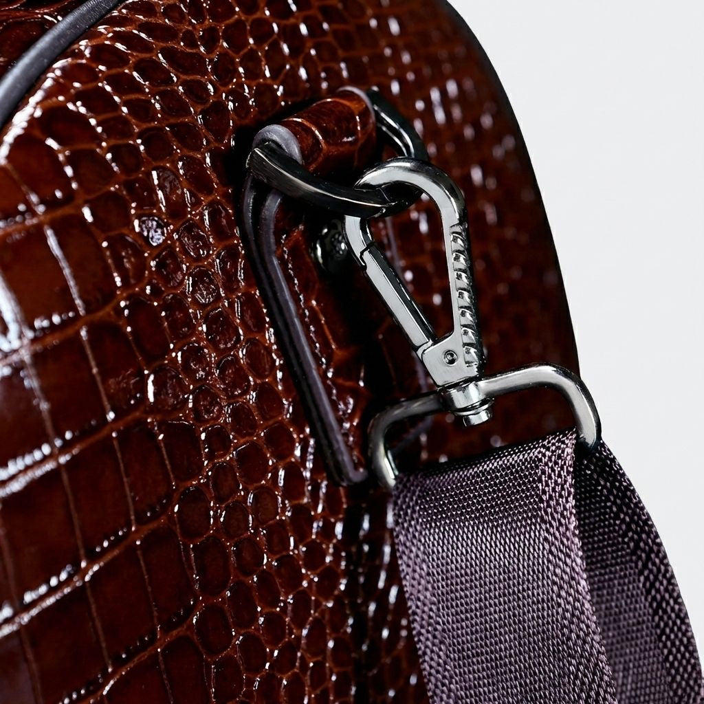 Gros plan sur le mousqueton argenté de la bandoulière attaché au sac de voyage cuir croco marron