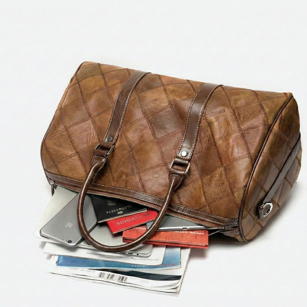 Sac de voyage cuir patchwork cognac ouvert, contenu visible : tablette, passeport, magazines et pochette
