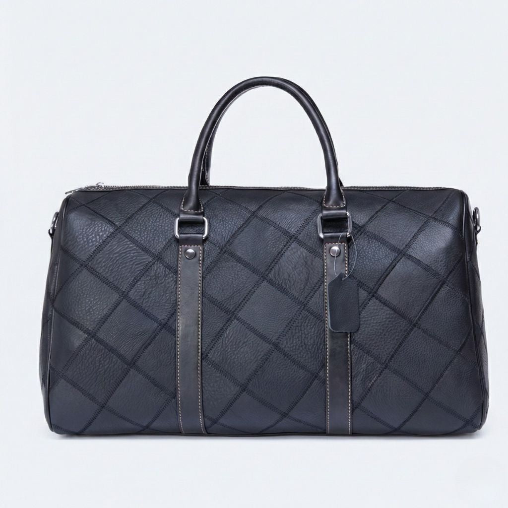 Vue de face du sac de voyage cuir patchwork grainé noir, étiquette bagagiste et coutures contrastées