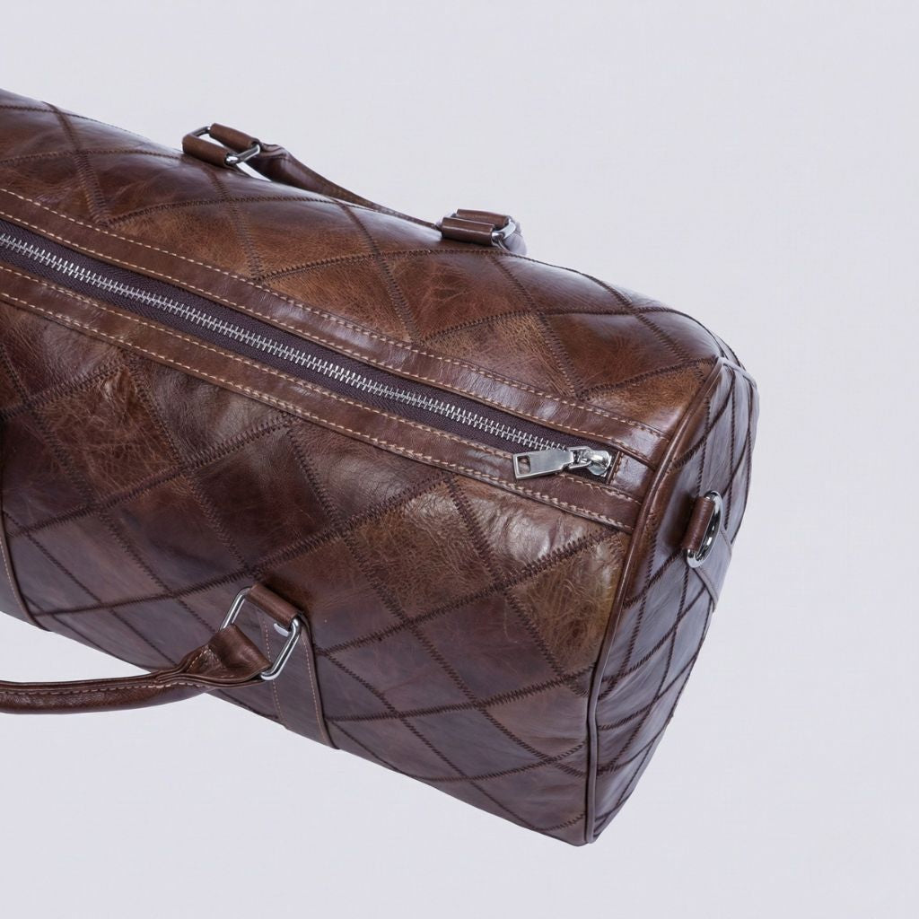 Gros plan sur la poche latérale zippée du sac de voyage cuir patchwork brun et sa quincaillerie argentée