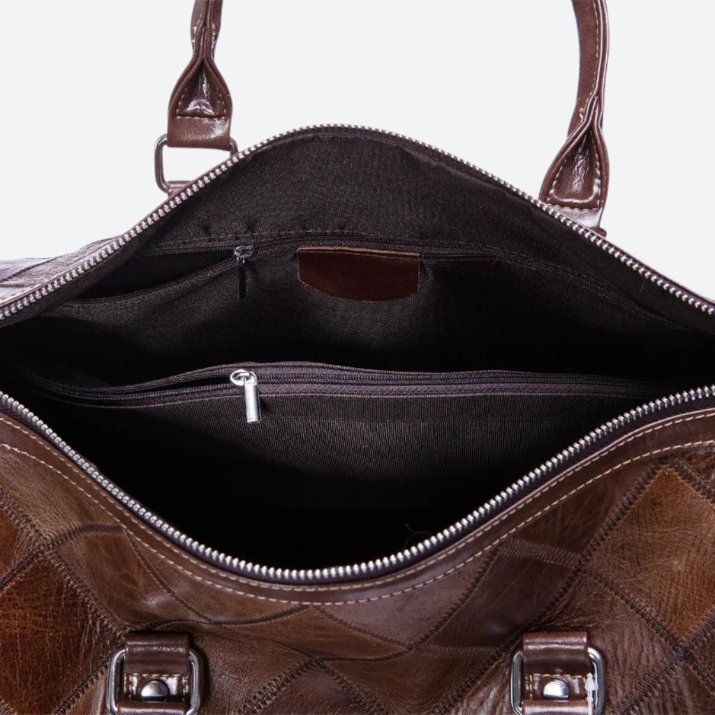 Vue de dessus du sac de voyage en cuir brun matelassé ouvert, intérieur noir avec poches zippées intégrées Image