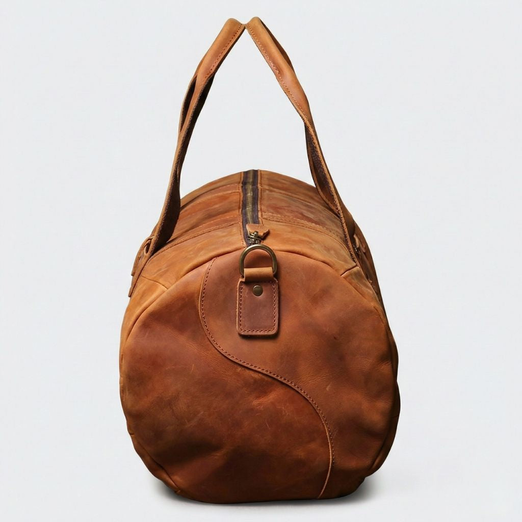 Vue du panneau latéral arrondi du sac de voyage cuir cognac vintage, anneau en D et attache poignée