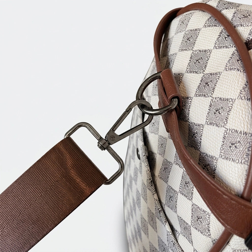 Gros plan sur le mousqueton métallique et l'attache bandoulière du sac week-end damier beige