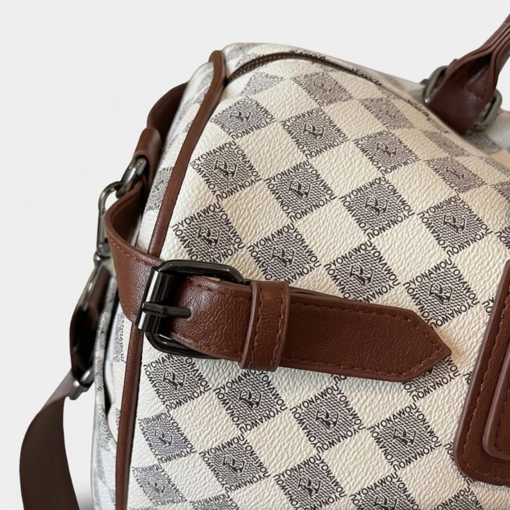 Gros plan sur la boucle décorative et l'attache mousqueton latérale du sac week-end damier beige