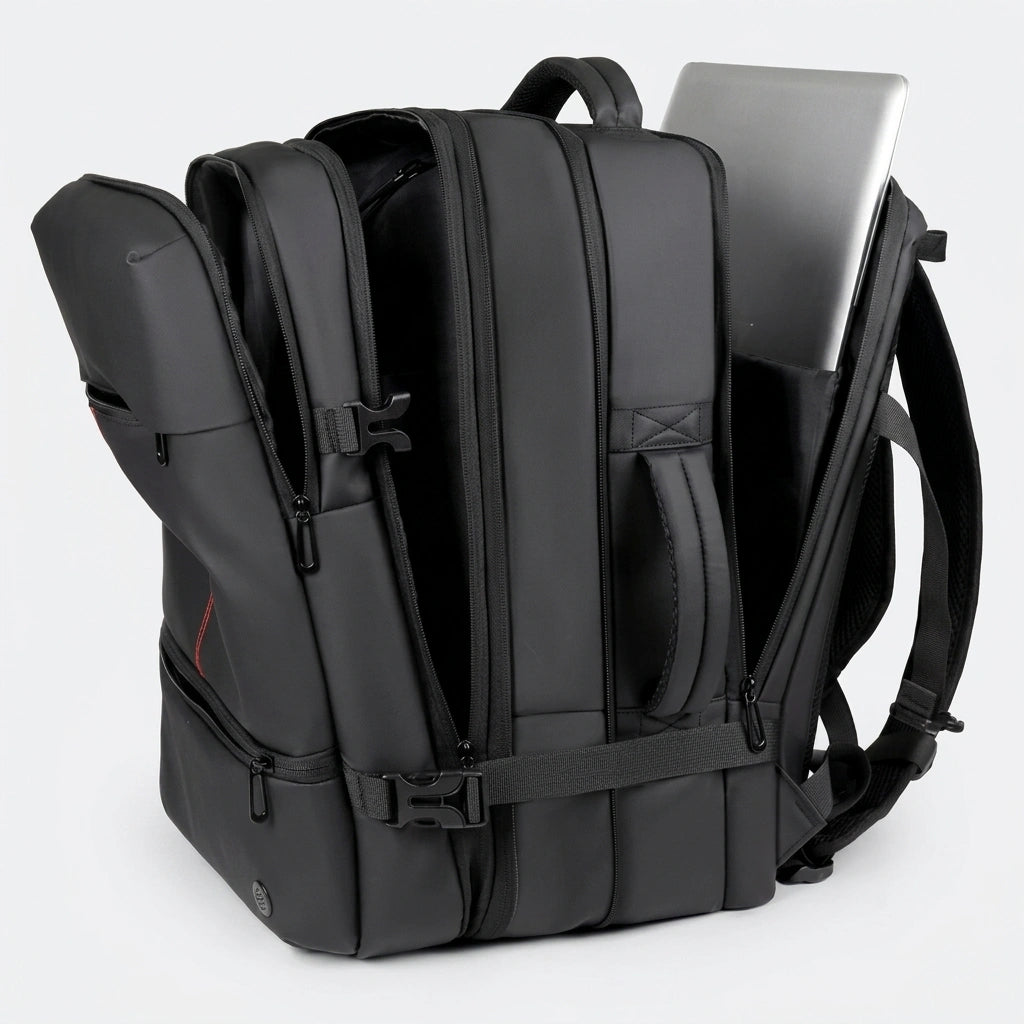 Sac à dos de voyage noir ouvert montrant les compartiments multiples et un laptop dans la poche arrière Image