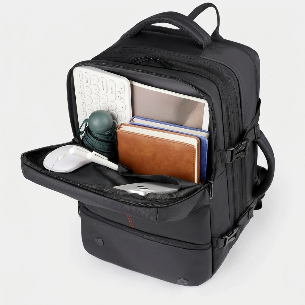 Compartiment principal du sac à dos business noir rempli avec clavier, carnets, gourde et accessoires
