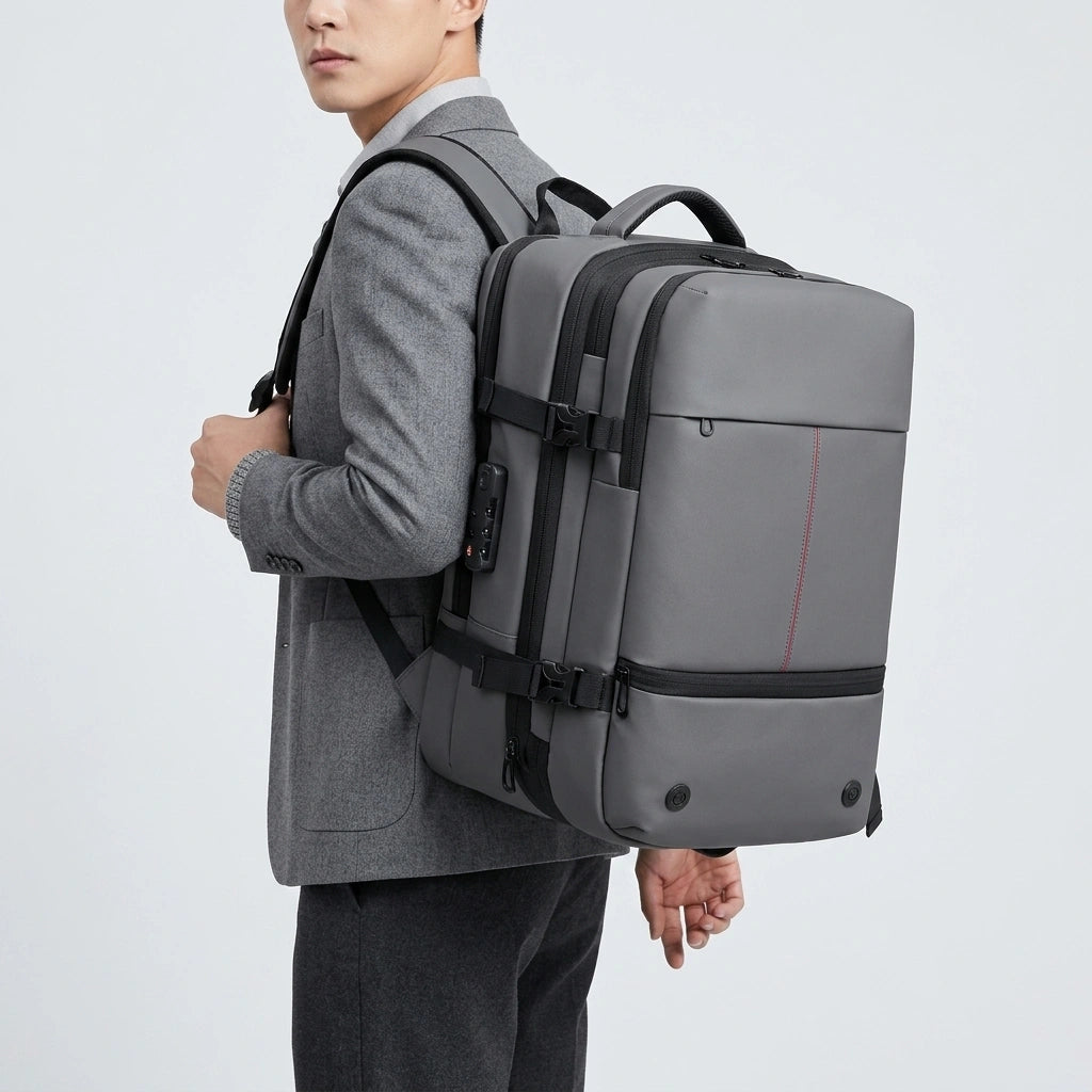 Homme en blazer gris portant le sac à dos de voyage extensible gris avec cadenas TSA visible de profil