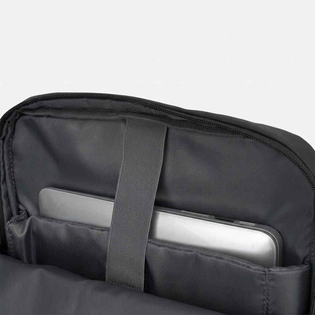 Compartiment laptop ouvert avec ordinateur portable maintenu par une sangle élastique dans le sac à dos de voyage