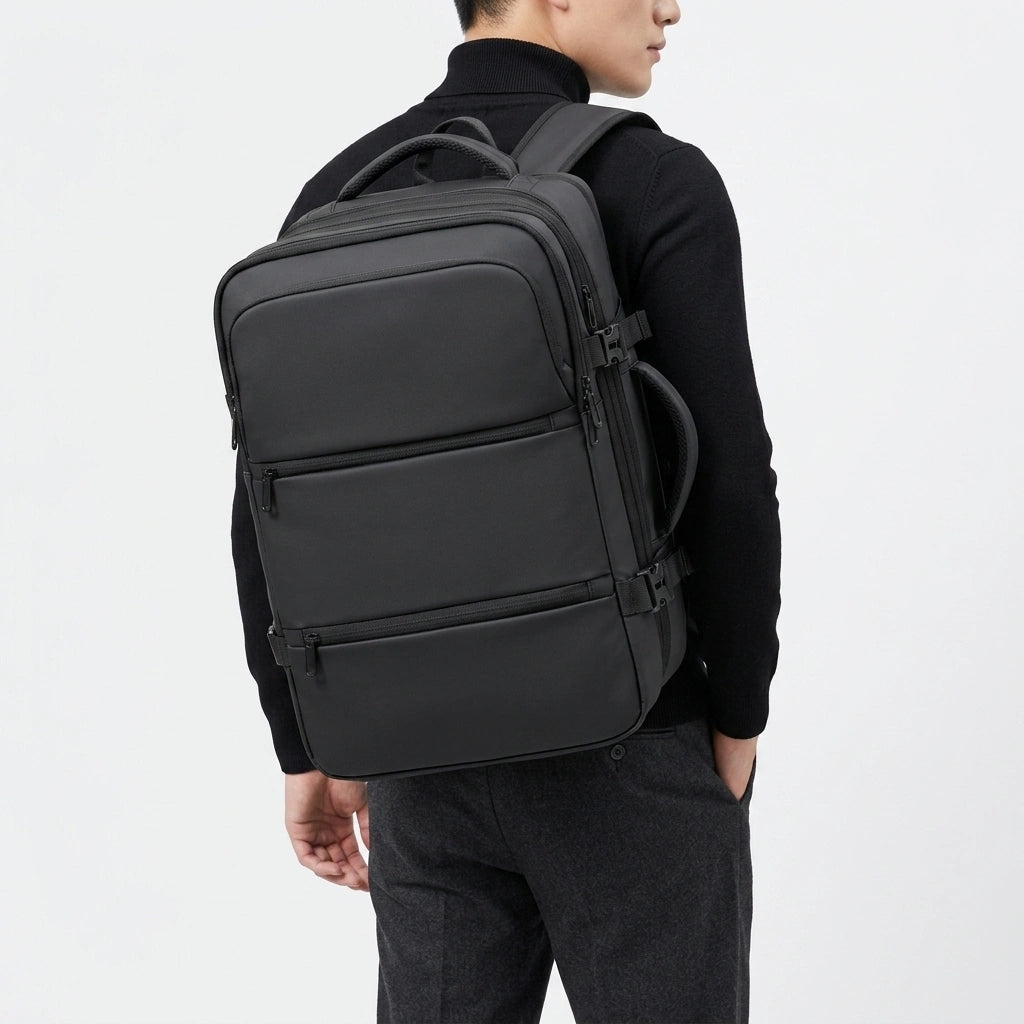 Homme en pull noir portant le sac à dos cabine noir vu de dos dans un style décontracté professionnel
