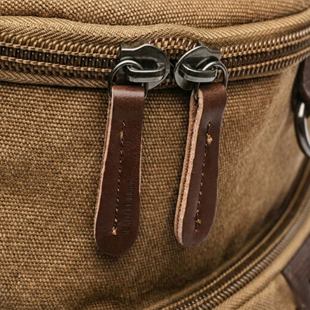 Gros plan sur les deux tirettes en cuir brun et la fermeture éclair de toile d'un sac à dos duffle Image