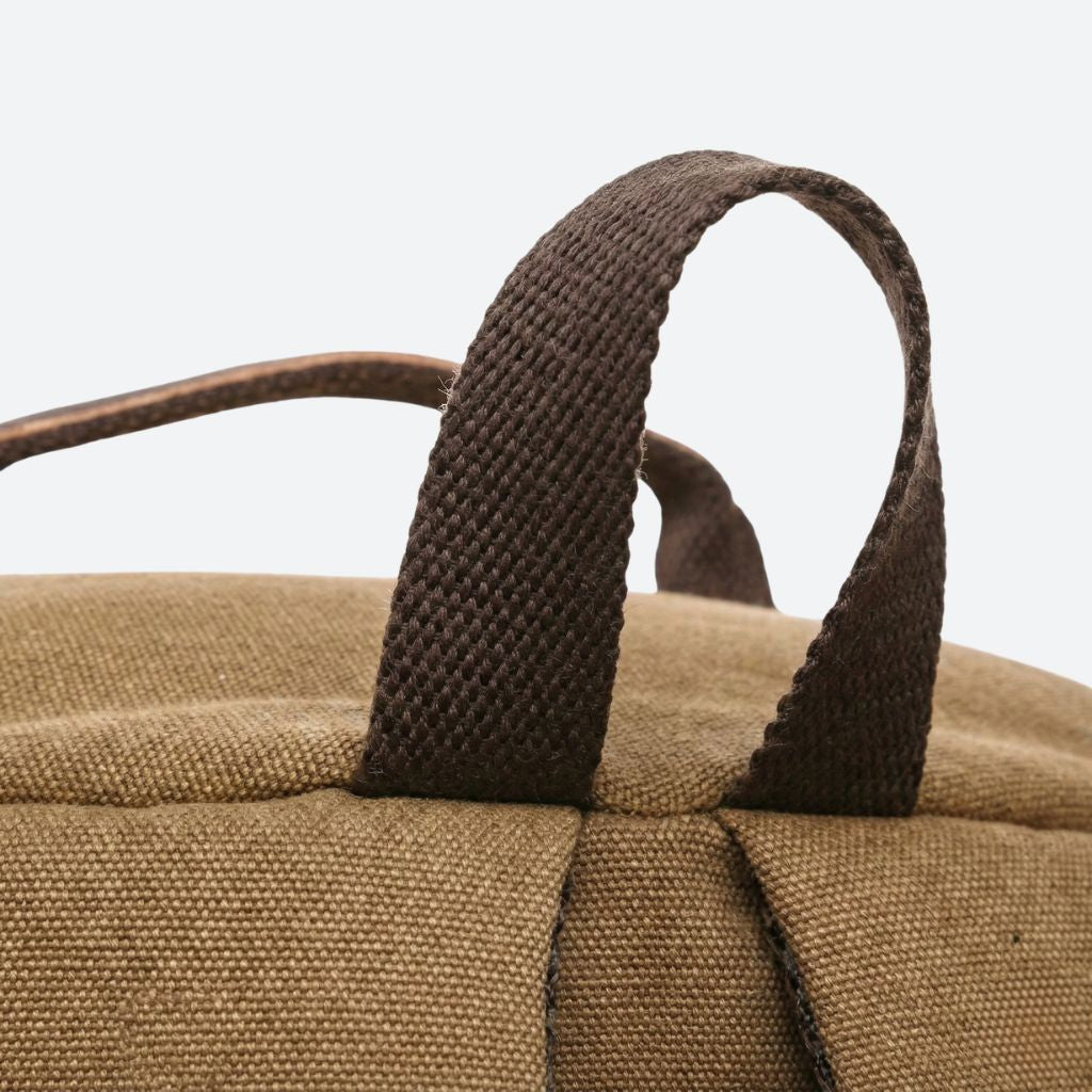 Gros plan des poignées textiles tressées marron du sac à dos duffle, solides pour un portage main confortable