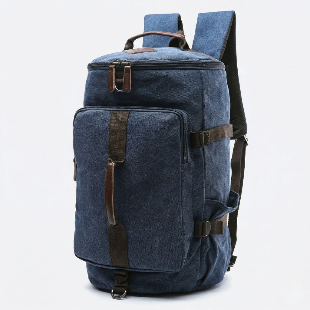 Vue 3/4 du sac de voyage duffle bleu marine convertible, toile lavée et finitions cuir marron sur les sangles