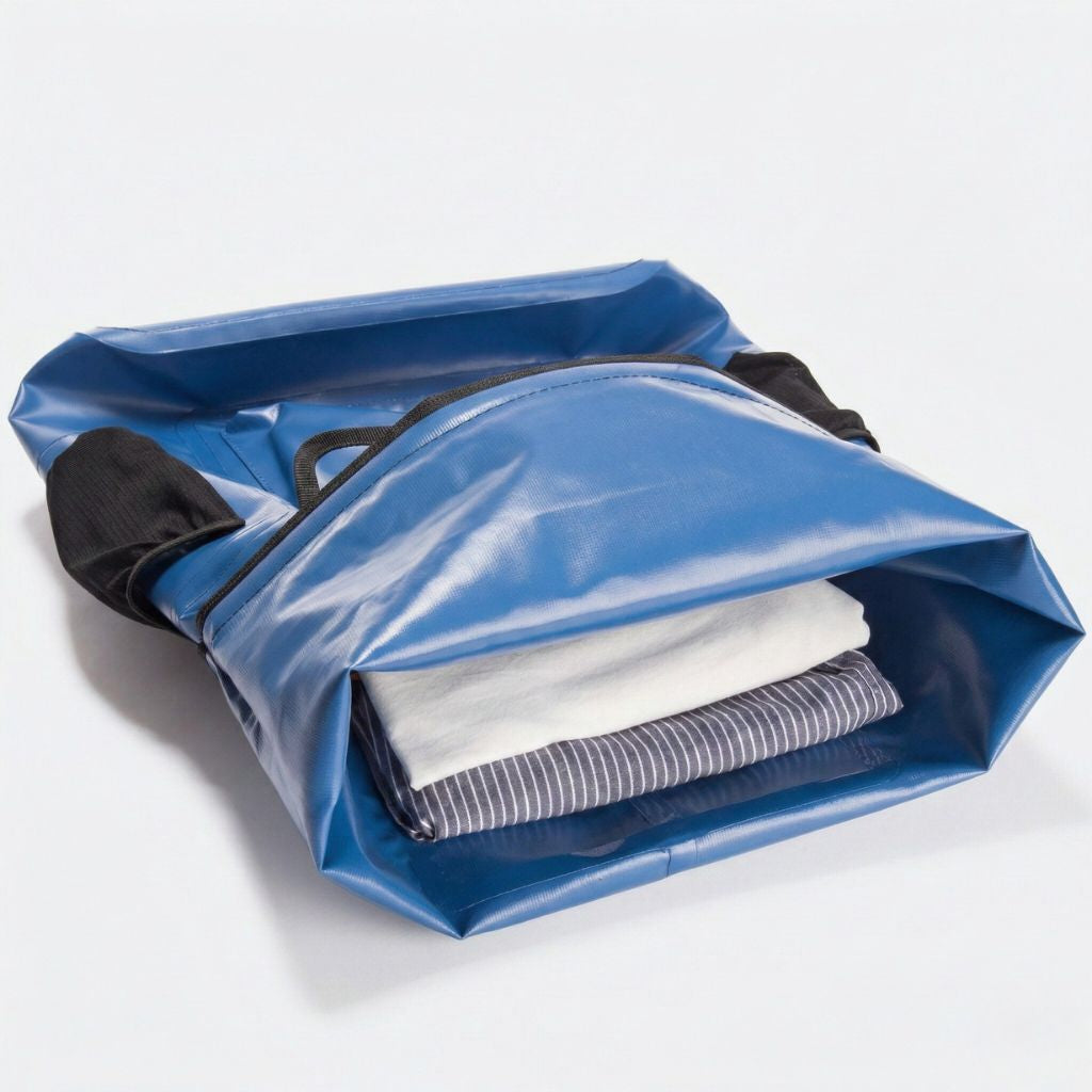 Compartiment d'un sac étanche bleu ouvert à plat avec poche organisateur et vêtements pliés rangés à l'intérieur Image