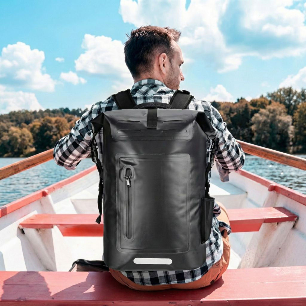 Homme assis à l'arrière d'une barque portant un sac à dos étanche noir roll-top avec bande réfléchissante Image