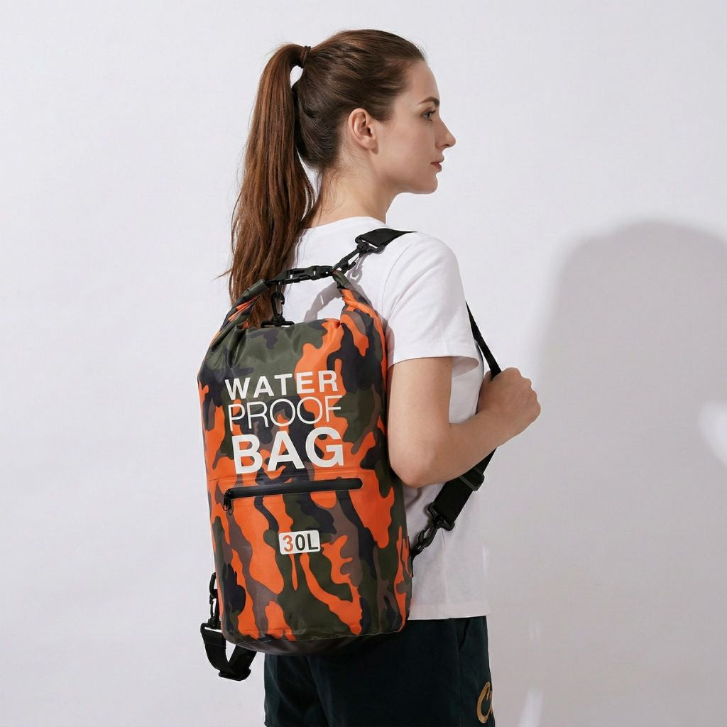 Femme portant un sac étanche camouflage 30L, vue 3/4 de profil, sangle de poitrine et bretelles ajustées