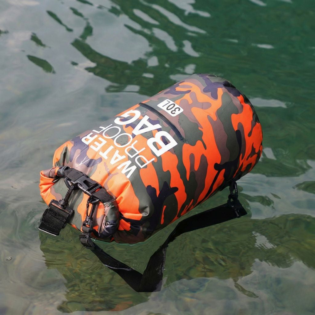 Sac étanche camouflage orange 30L roll-top posé sur l'eau illustrant sa flottabilité et son imperméabilité Image
