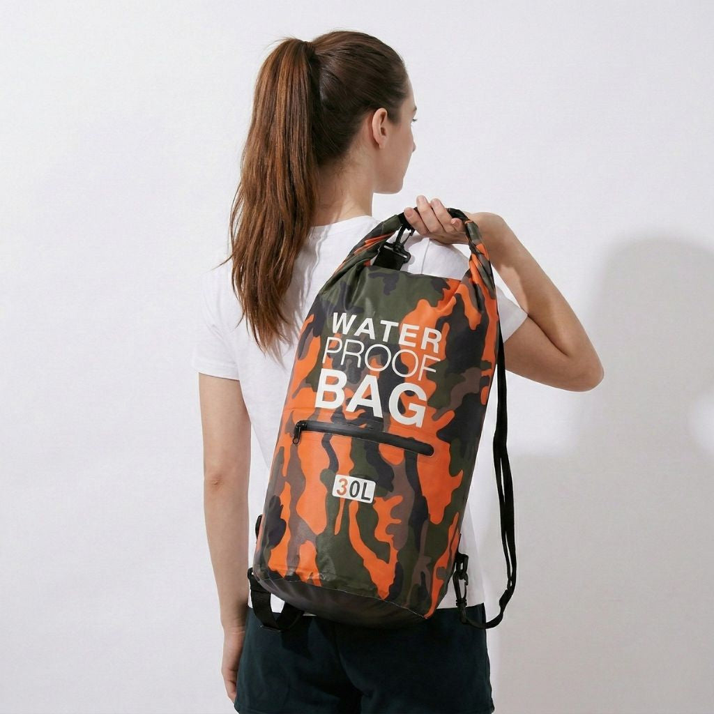 Femme portant un sac étanche camouflage 30L dans le dos, vue de dos, fermeture roll-top et bretelles visibles