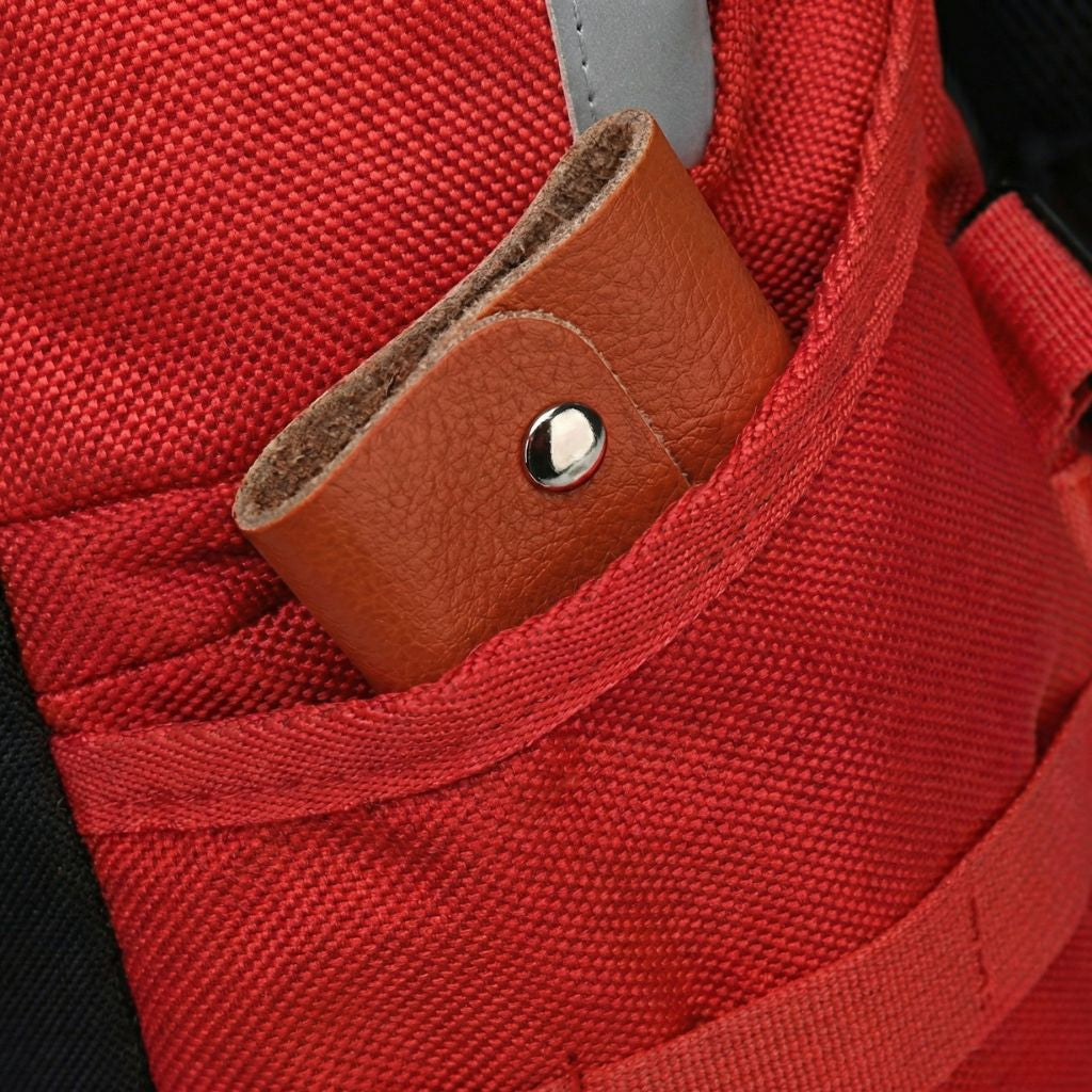 Gros plan sur la petite poche inférieure du sac à dos rouge avec languette en cuir et bouton pression