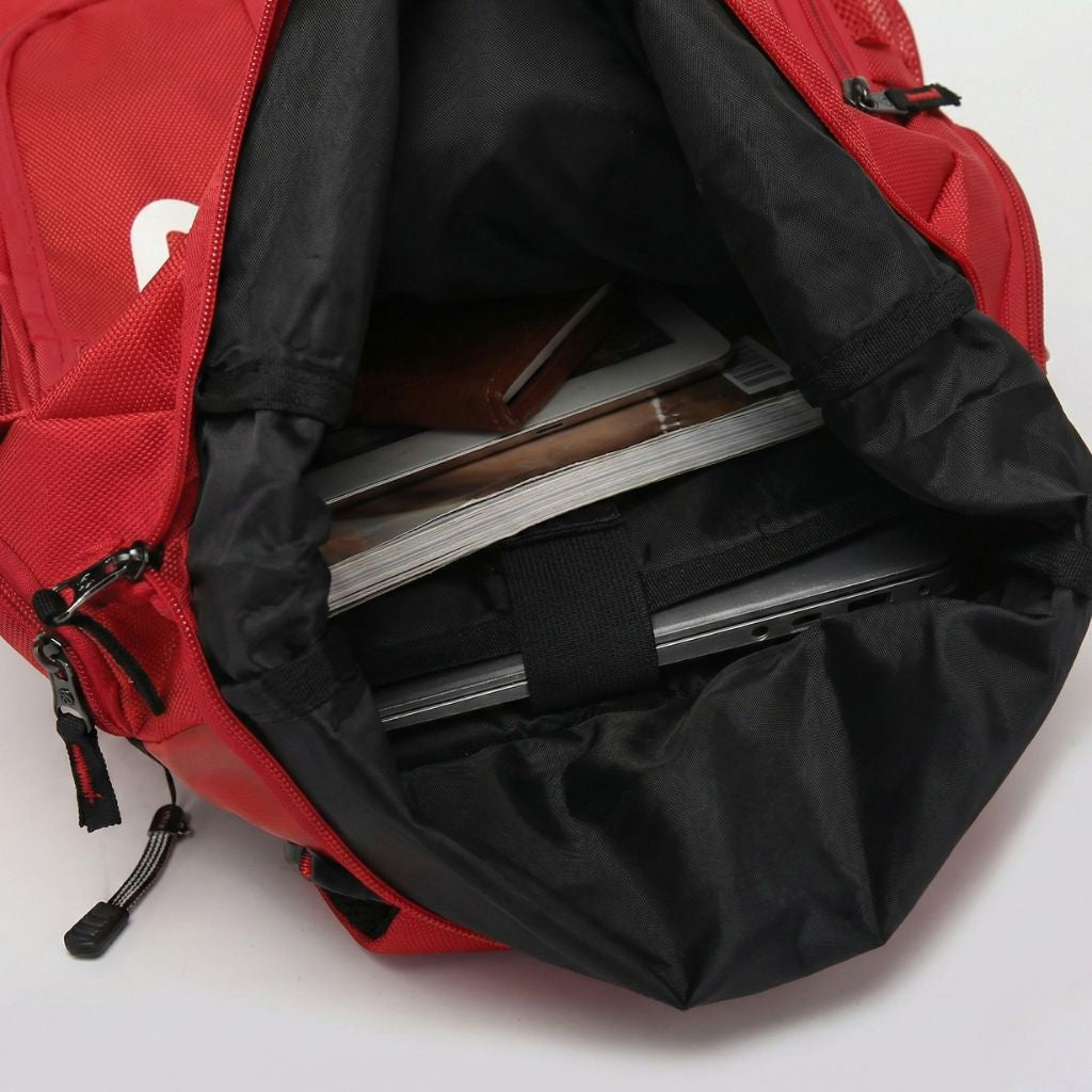Vue plongeante dans le compartiment roll-top d'un sac à dos étanche rouge avec ordinateur portable et carnets Image
