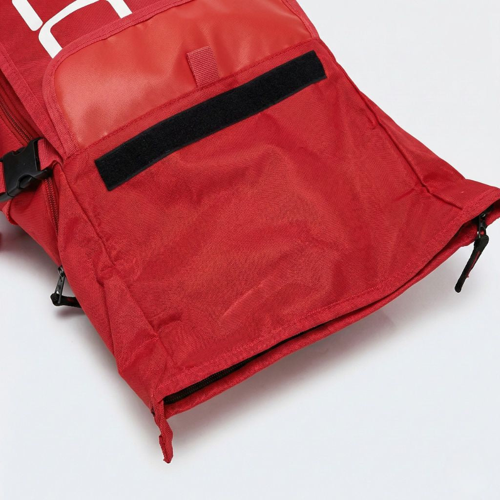 Gros plan sur le compartiment frontal ouvert d'un sac à dos étanche rouge avec poche velcro et accès zippé Image
