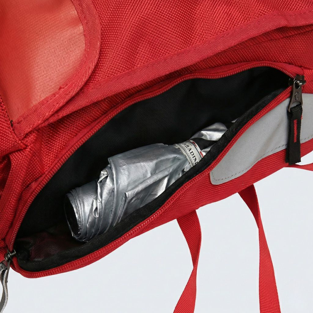 Poche latérale du sac à dos rouge ouverte révélant un parapluie replié et un liseré réfléchissant