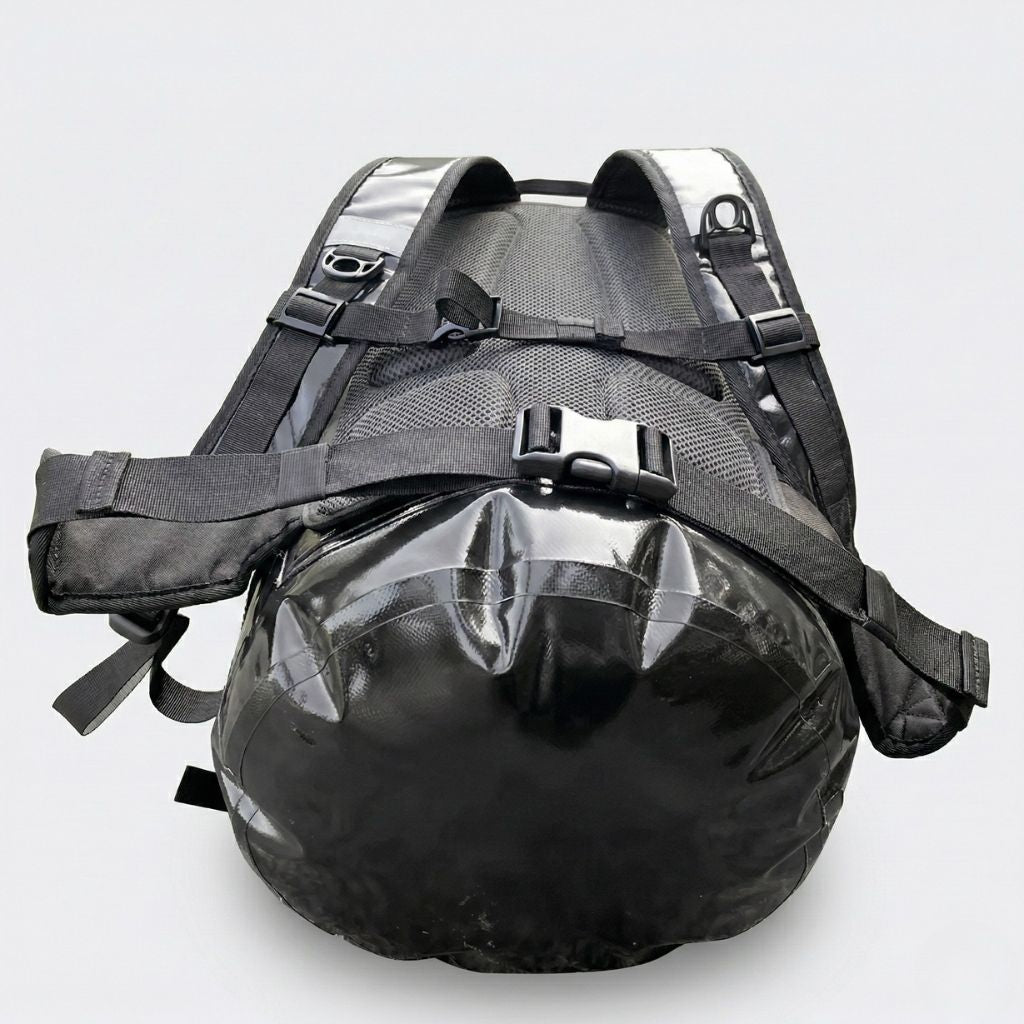 Vue de dessous du sac étanche noir montrant le harnais avec dosseret mesh et ceinture ventrale à boucle