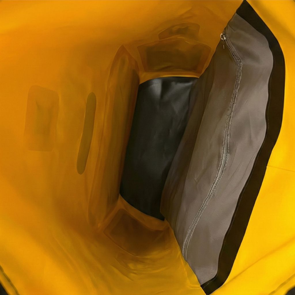 Intérieur du sac étanche jaune roll-top vu du haut, parois translucides et poche zippée intérieure grise