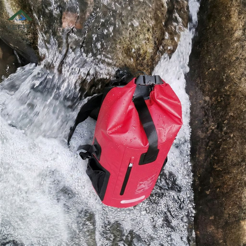 Sac à dos étanche rouge posé sur des rochers près d'une cascade, illustrant son imperméabilité en milieu naturel Image