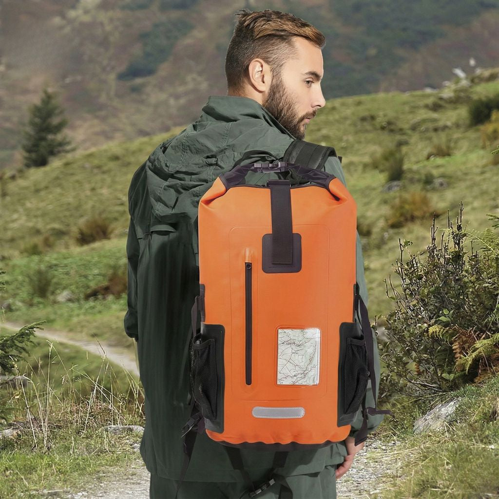 Randonneur portant un sac à dos étanche orange 30L en montagne, fenêtre frontale avec carte topographique visible