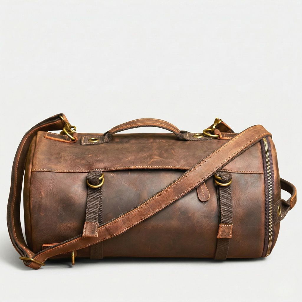 Sac de voyage cylindrique en cuir marron vintage, bandoulière croisée, sangles canvas et boucles laiton doré