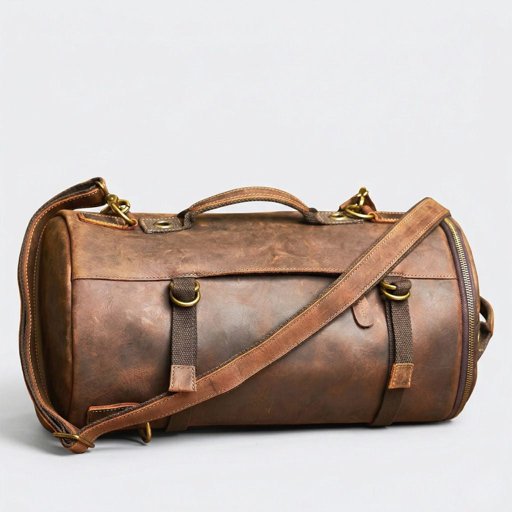 Vue trois-quarts du sac cylindrique cuir brun patiné, sangles canvas kaki et boucle laiton en mode duffle