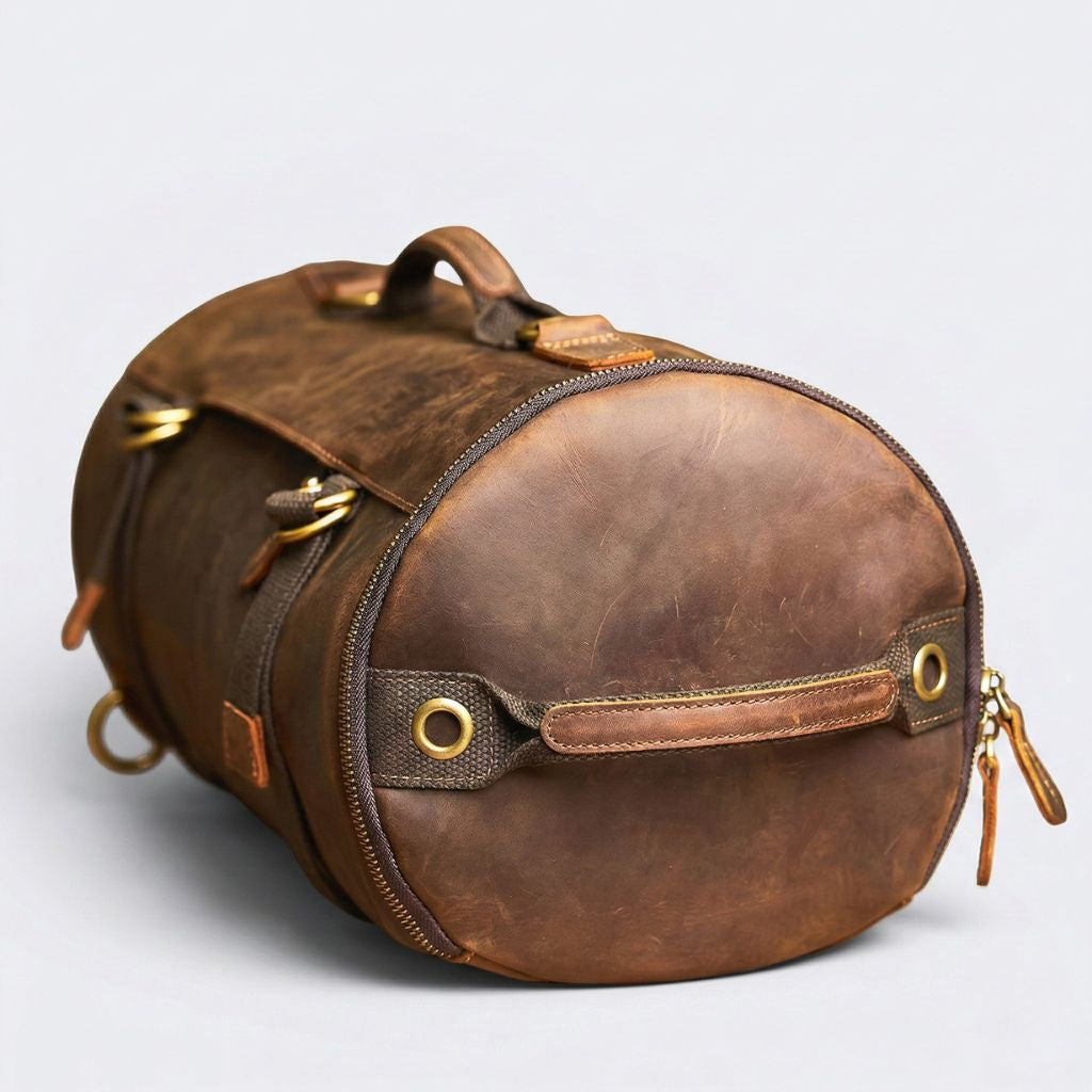 Fond circulaire du sac en cuir marron patiné, fermeture zippée périphérique et sangle canvas à œillet