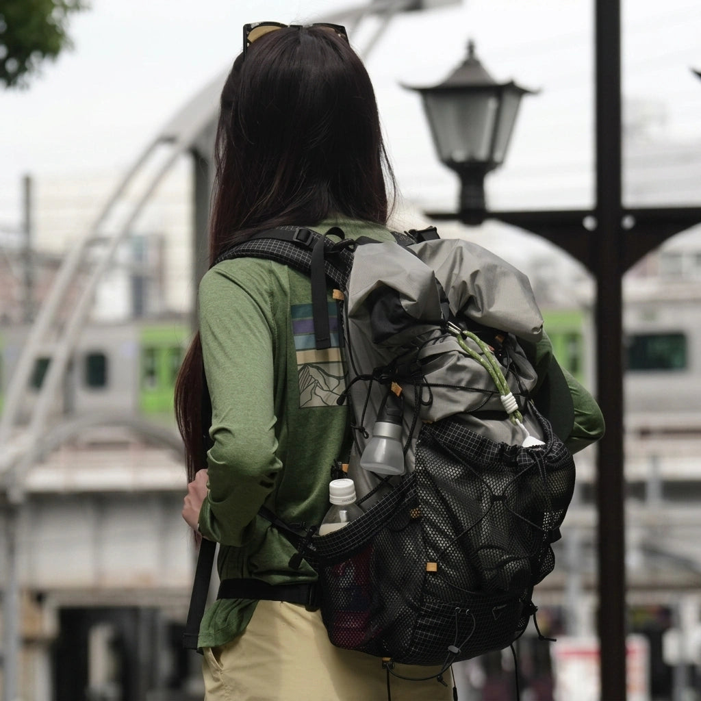 Femme de dos en ville portant un sac à dos de voyage gris ultraléger 35L avec bouteilles dans les poches latérales Image
