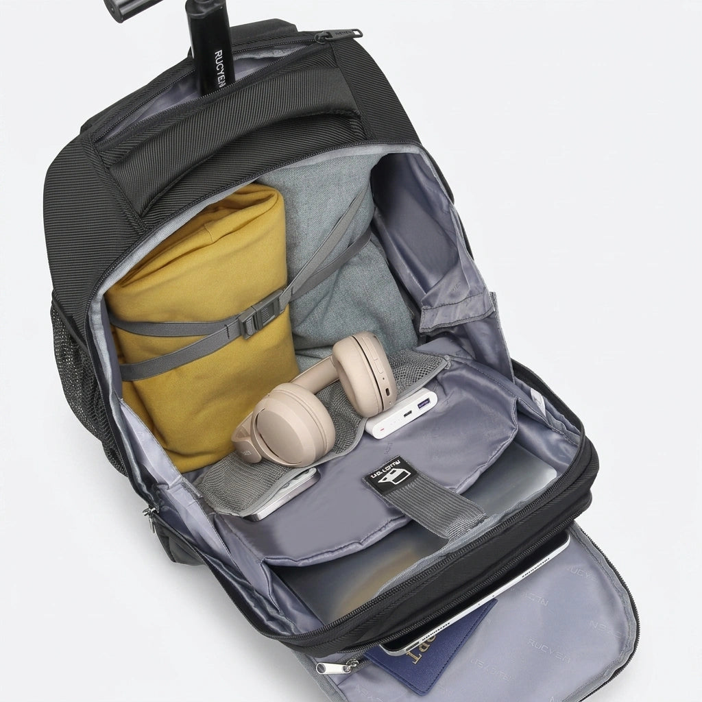Intérieur du sac à dos trolley 33L ouvert, casque beige, vêtements jaune et gris, laptop et accessoires