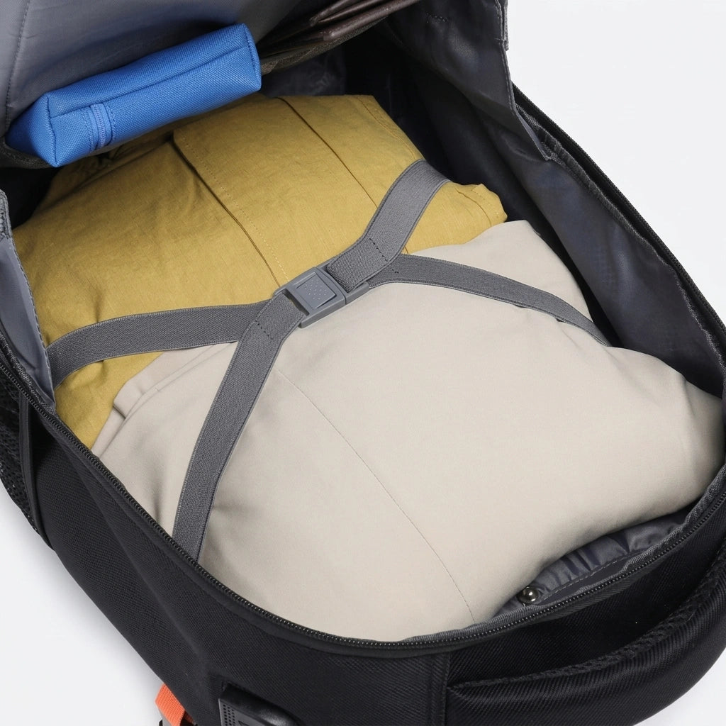 Compartiment principal du sac à dos trolley 33L ouvert, vêtements jaune et beige retenus par sangles