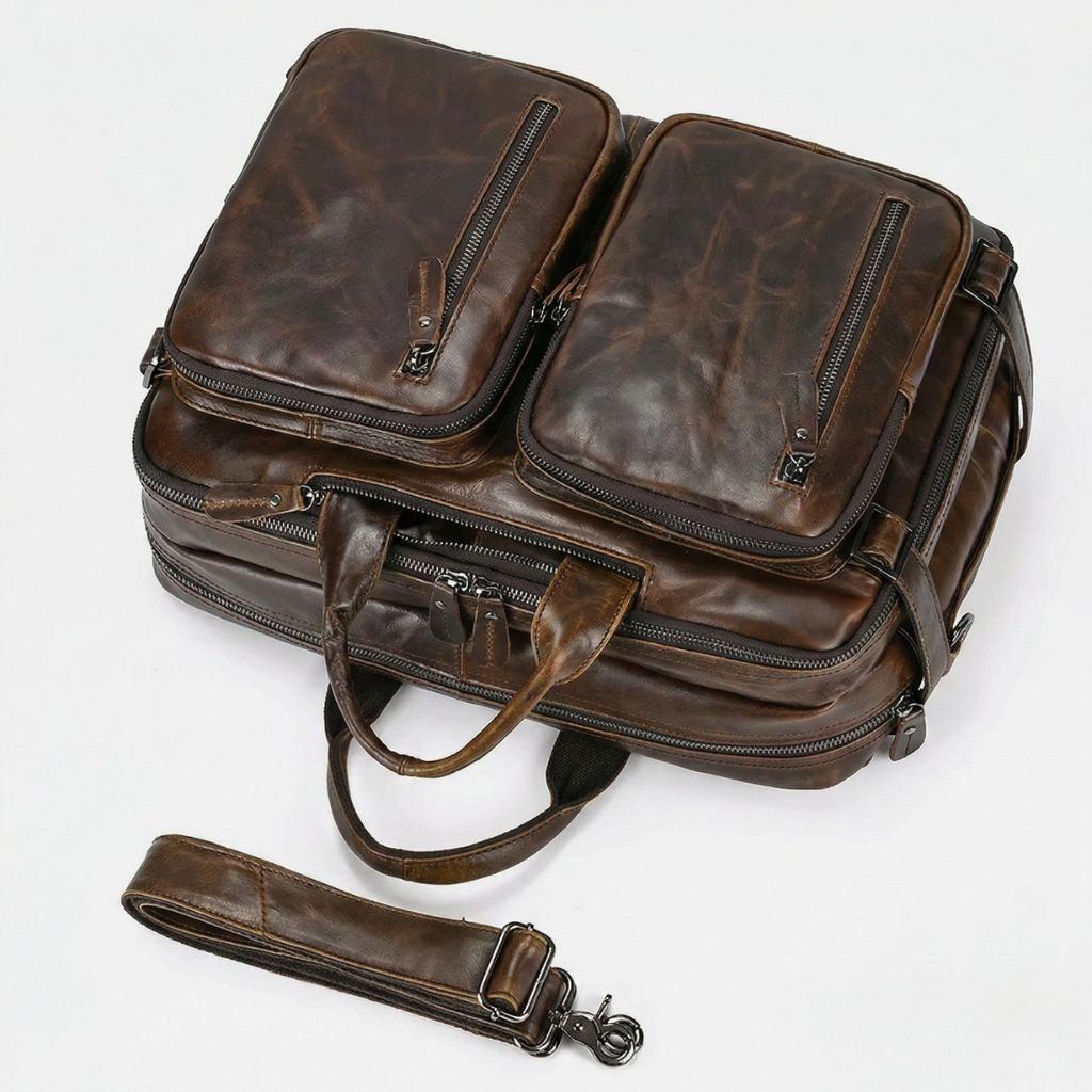 Vue plongeante sur les deux poches avant bombées en cuir marron vintage et la bandoulière déployée