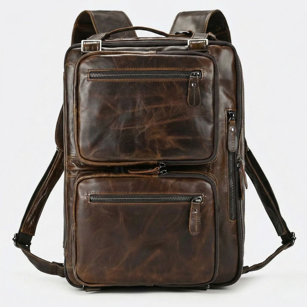 Sac marron foncé configuré en sac à dos, bretelles larges cuir déployées, deux poches frontales zippées